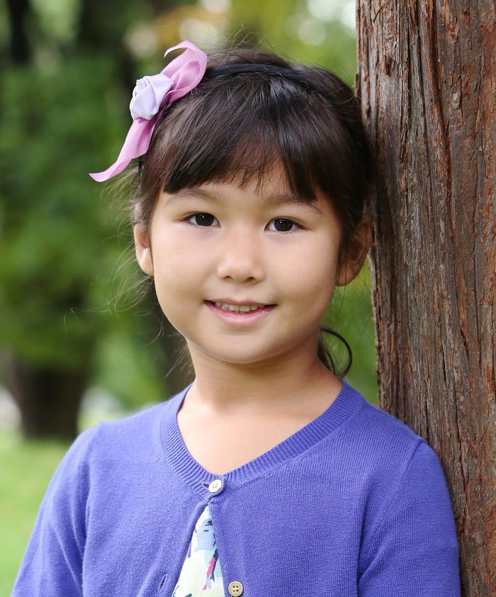 A portrait of a young girl against a tree by Tim Macdonald