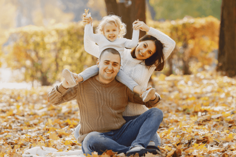 A family poses outside in fall leaves