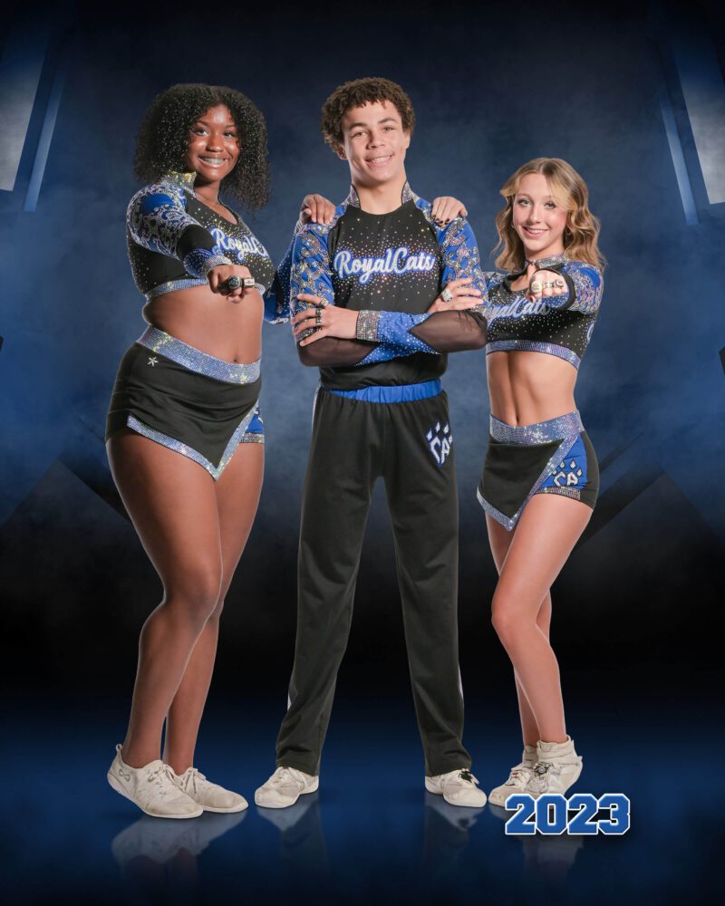 A group of three cheerleaders smiles and poses